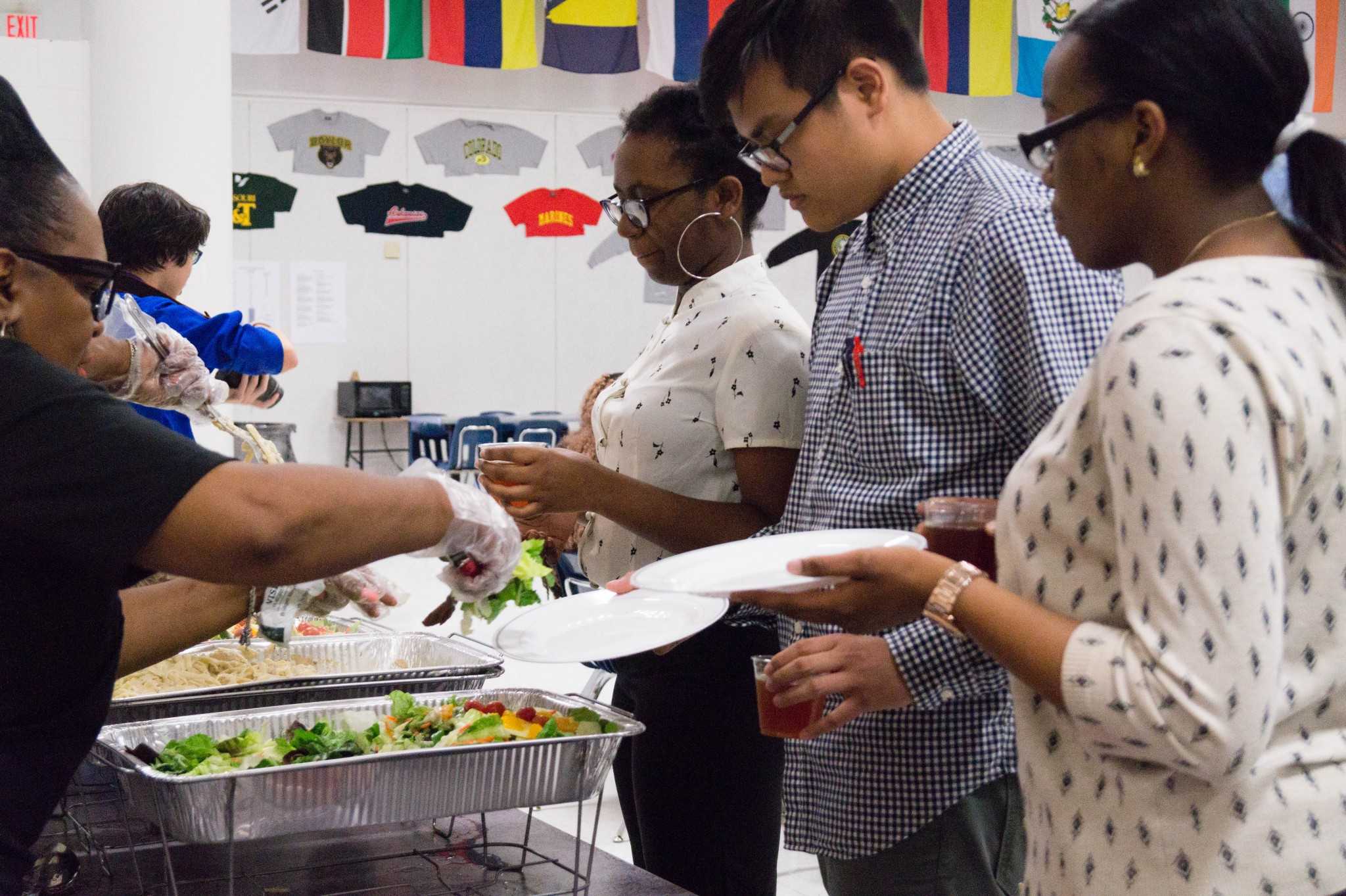Duy Vo (12), Ashley Gwananji (12), and Vina Nweke (12) wait and anticipate on getting their delicious Alfredo and salad for the Eating Etiquette Workshop where they learn how they should eat in professional dinner settings.