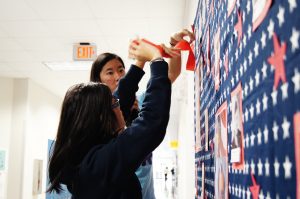 Seniors Tam Vu and Linda Le use streamers to decorate the traditional Veterans' Day wall. 