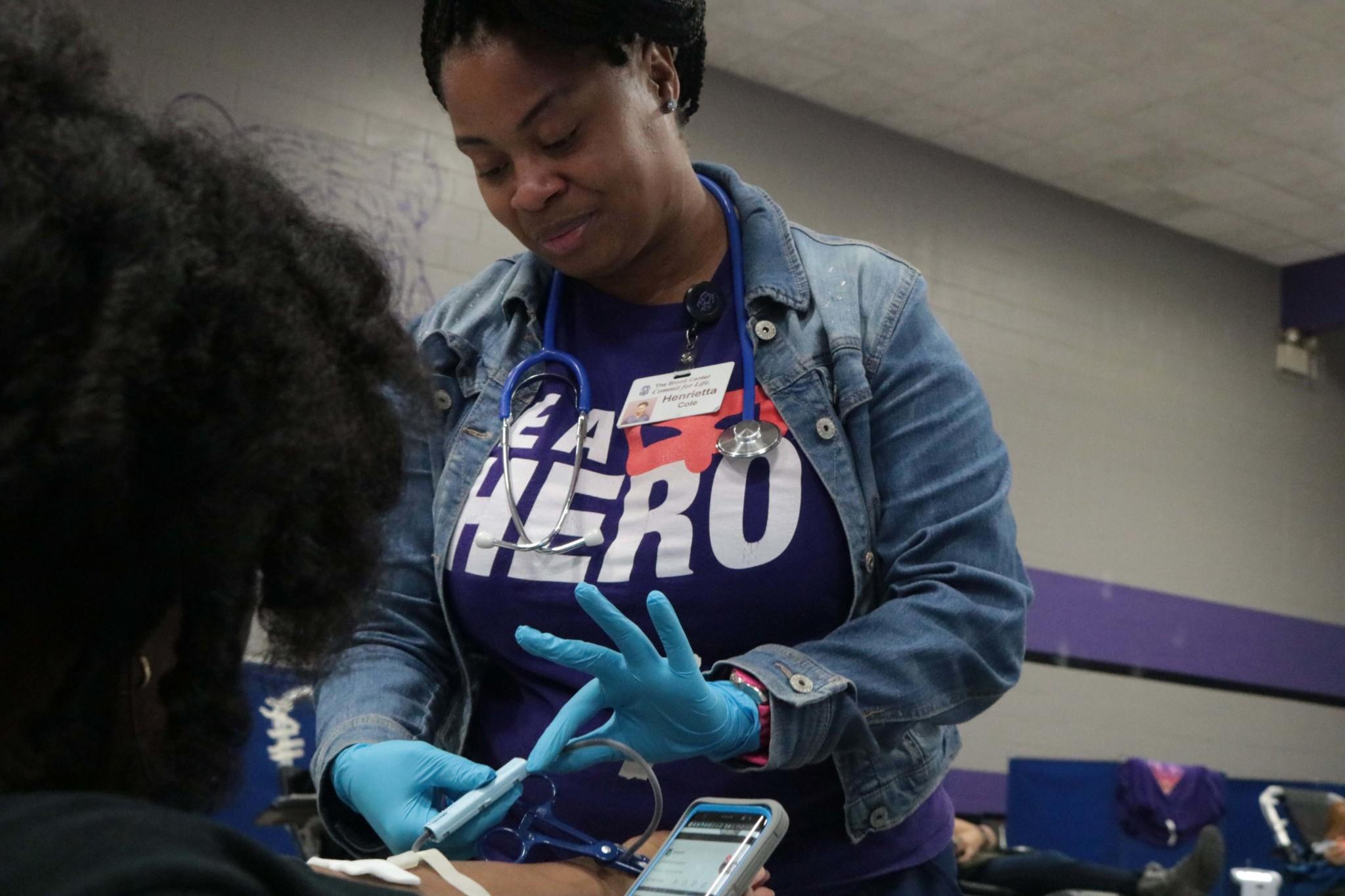 Henrietta Cole, the blood center phlebotomist, sticks needle into Dominique Carter’s arm to extract blood for the donations.