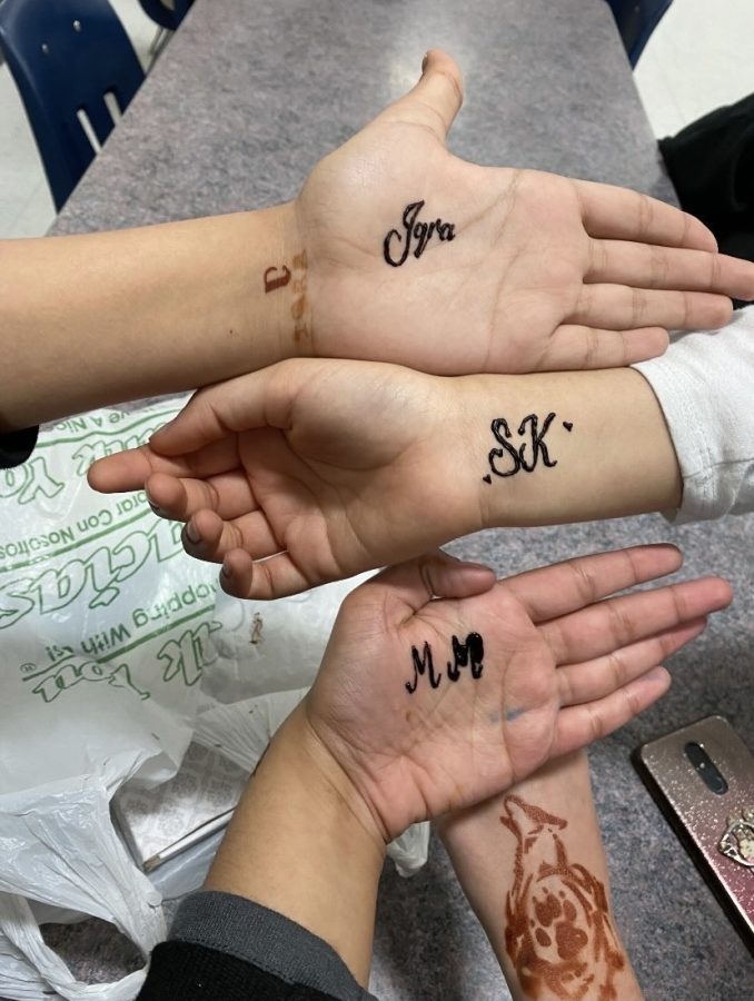 Kerr studnets getting henna of their names/initials on their hands for Eid