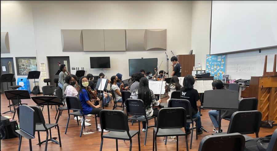Orchestra students practice in a group. The student standing is the director, helping others to play in-tune with each other. Tomorrow will be Orchestra Day.