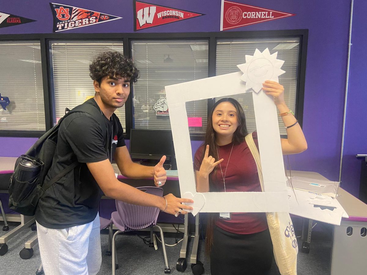 A photo of two people holding a uncompleted cutout to take pictures with.