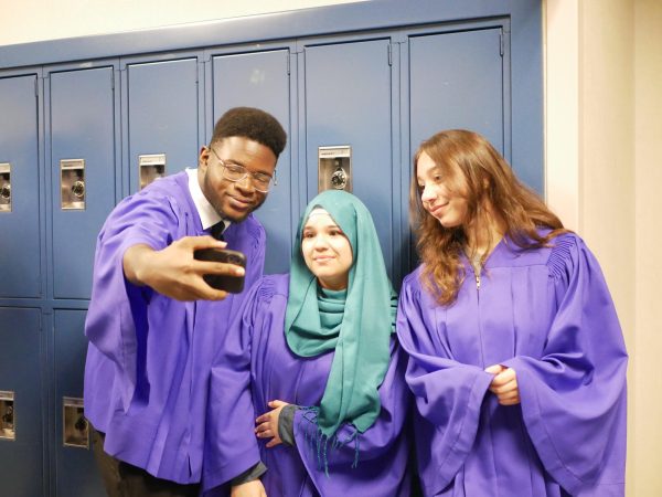 Seniors Shadrack Akinkunmi, Manar Al-Gburi, and Sarah Abi Saab take a photo by lockers. They waited for the photographers to finish setting up before taking their yearbook photo. "This is the read deal," Akinkunmi said.