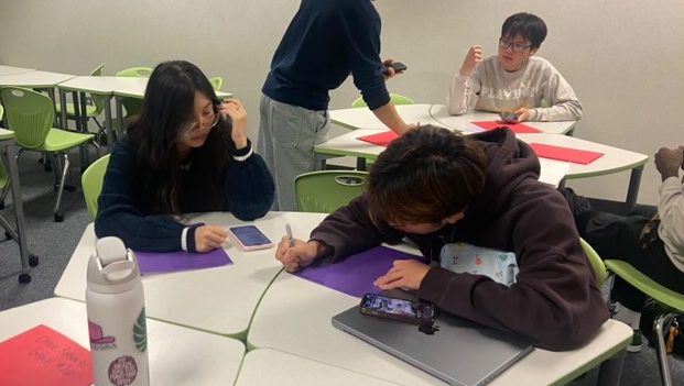 Lead mentors in Action: Taylor Nguyen and Janet Duong write down their names and group numbers on folders. They will use the folders to hold all the attendance sheets and handouts for this year. "I'm excited to meet all the people in my group," Taylor Nguyen said.