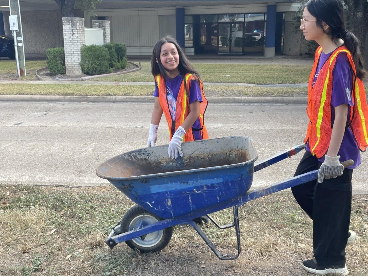 Carrying The Load:  Treasurer Jenny Luong and member Emely Vicente help by moving mulch to each newly planted tree. They planted trees across Alief’s Wilcrest block. “It was hard carrying the wheelbarrow but it was still fun,” Luong said. 
