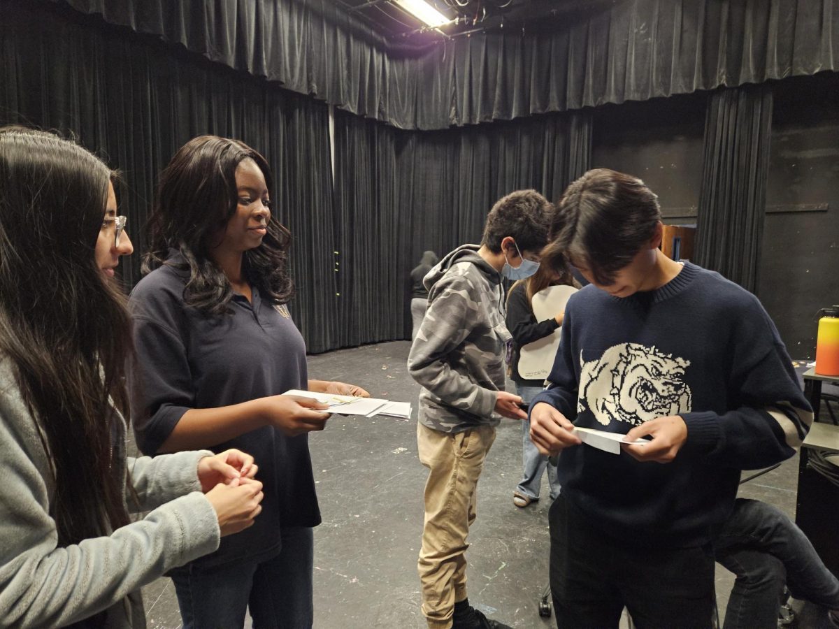 Welcomed With Open Arms: Treasurer Beyonce Vallecillo and Secretary Rebecca Oyeniyi pin inductee. Oyeniyi hands the inductee his acceptance envelope while Vallecillo pins him with the club's colored ribbons. "It was kind of awkward," Oyeniyi said. 