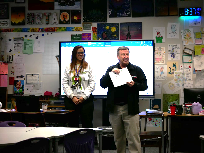 Anticipating Win. Math Teacher Karen Orta receives certificate from Sales Manager Mike Biglow. Orta also received a full package of perks. "I will go here with my kids," Orta said.