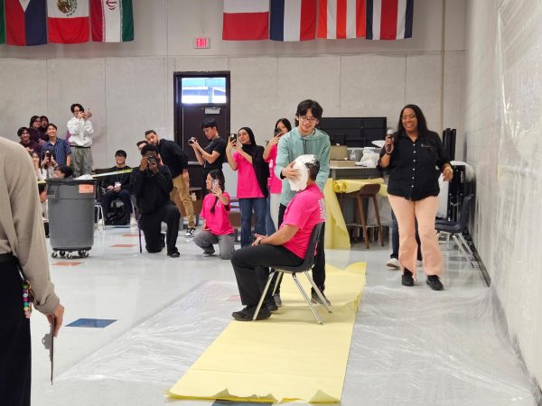 Pie flies, teacher cries: Esai Alvear Moreno pies Band Director Nikola Nikolovski. In between the alphabet auction, students had a chance to pie one of the teachers. "We just wanted to have some fun, and it felt gratifying to pie him," Moreno said.